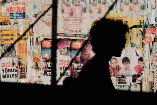 shadow of a person against a collage of posters