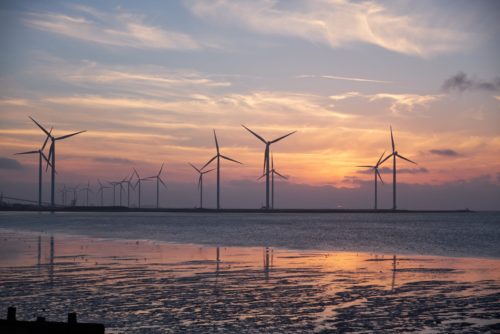 Sunset photo of wind turbines by the sea