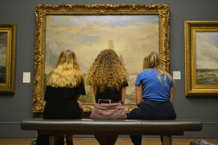 3 women looking at painting