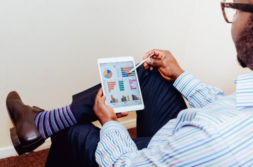 person working on a tablet with graphs on it