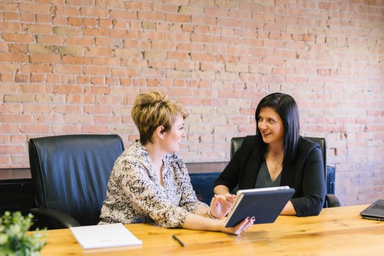 women discussing something they are looking at on a tablet