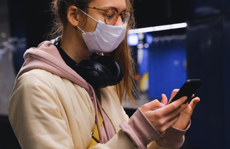 A woman wearing a mask on a mobile phone