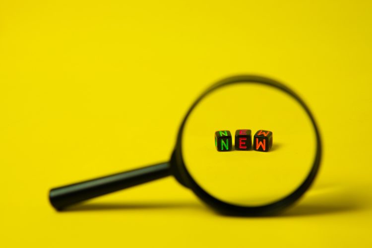 A magnifying glass focused on beads that spell out new