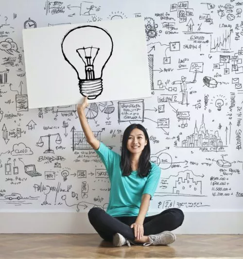 A woman holding up a sign with a lightbulb drawn on it