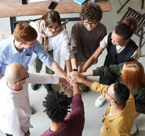 A group of people in a circle with their hands in together.